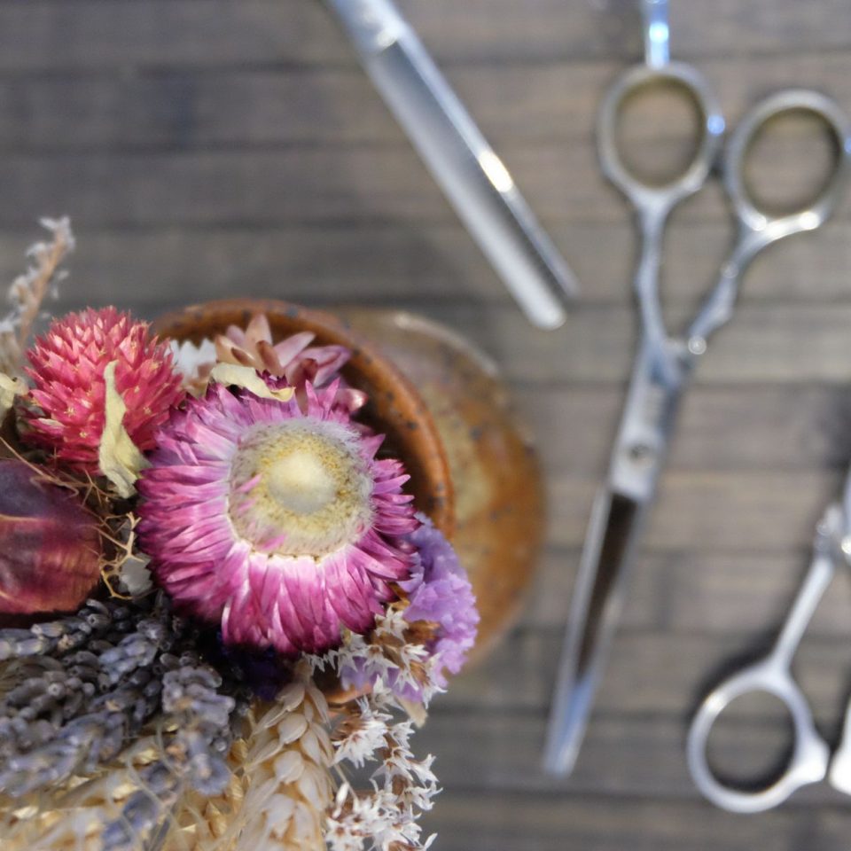 bouquet de fleurs séchés et trois paires de ciseaux sur une table en bois